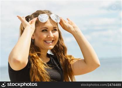 Happy teen woman enjoying her leisure time. Female having long brown hair posing with sky in background. Happy teen woman against clouds