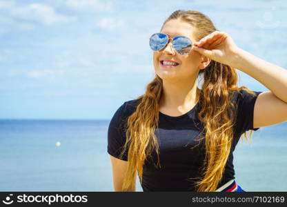 Happy teen woman enjoying her leisure time. Female having long brown hair posing with sky in background. Happy teen woman against clouds