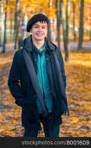 Happy teenage boy in the autumn sunny park. Happy smiling teenage boy in a beret and jacket in the autumn sunny park