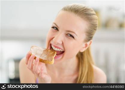 Happy teenage girl eating toast with chocolate cream