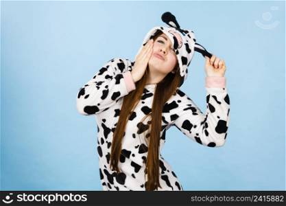 Happy teenage girl in funny nightclothes, pajamas cartoon style making silly face, positive face expression, studio shot on blue.. Woman wearing pajamas cartoon making silly face
