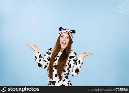 Happy teenage girl in funny nightclothes, pajamas cartoon style, positive surprised face expression, studio shot on blue. Advertisement concept. Woman wearing pajamas cartoon surprised face