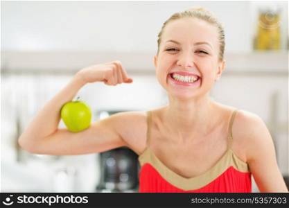 Happy teenage girl showing biceps and apple
