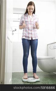 Happy Teenage Girl Standing On Bathroom Scales