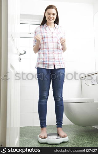 Happy Teenage Girl Standing On Bathroom Scales