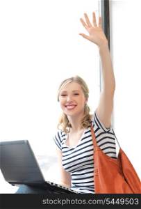 happy teenage girl waving a greeting with laptop