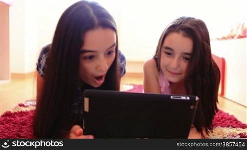 Happy teenage girls having fun using tablet computer at home