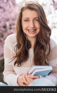 Happy teenage student with braces holding book outside