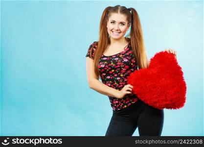 Happy teenage woman holding heart shaped pillow. Valentines day gift ideas concept.. Happy woman holding heart shaped pillow