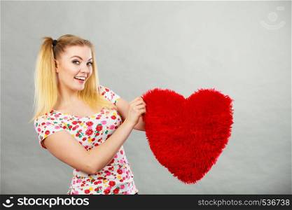 Happy teenage woman holding heart shaped pillow. Valentines day gift ideas concept.. Happy woman holding heart shaped pillow