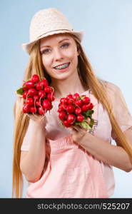 Happy teenage young woman ready for summer wearing pink outfit and sun hat giving showing delicious radish. Happy woman giving radish