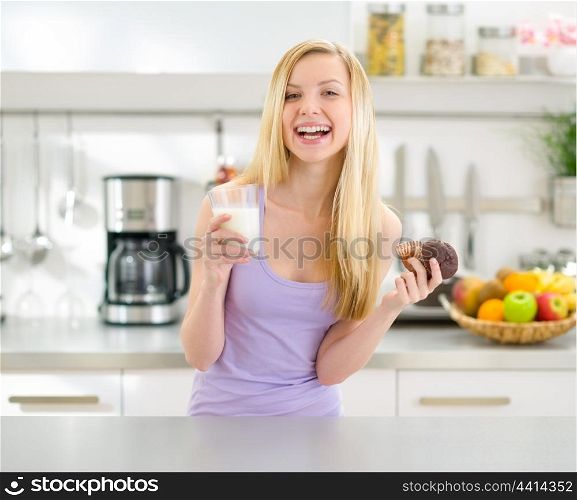 Happy teenager girl eating chocolate muffin with milk