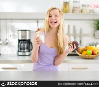 Happy teenager girl eating chocolate muffin with milk