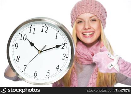 Happy teenager girl in winter hat and scarf showing clock and thumbs up
