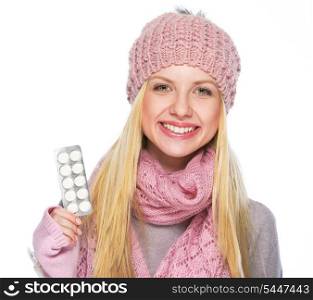 Happy teenager girl in winter hat and scarf showing pills pack
