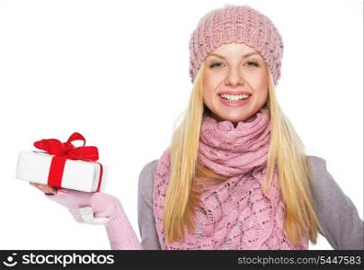 Happy teenager girl in winter hat and scarf showing presenting box
