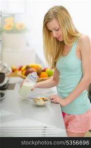 Happy teenager girl making breakfast in kitchen