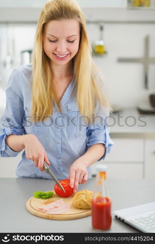 Happy teenager girl making sandwich in kitchen