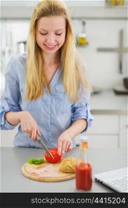 Happy teenager girl making sandwich in kitchen