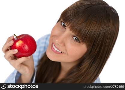 Happy teenager in pajamas eating healthy apple for breakfast on white background