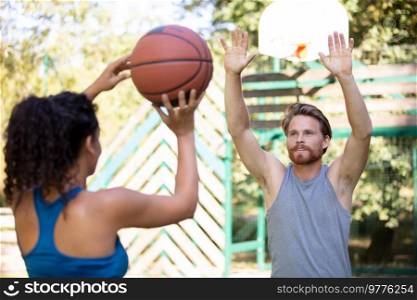 happy teenagers playing basketball outdoors