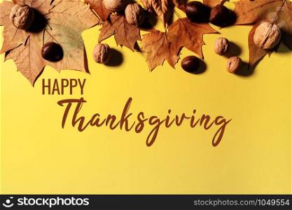 Happy Thanksgiving Day with maple leaves and nut on yellow background