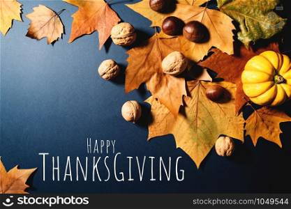 Happy Thanksgiving Day with maple leaves, nut and pumpkin on blue background