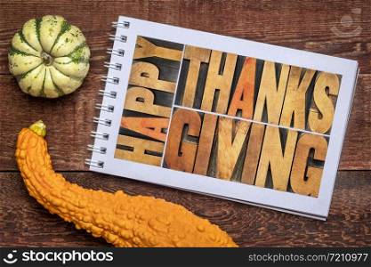 happy thanksgiving greeting card - letterpress wood type lettering in a sketchbook against rustic wood with ornamental gourd