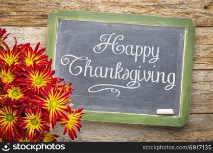 Happy Thanksgiving greeting card - white chalk text on a vintage slate blackboard with a pot of mums