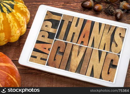 Happy Thanksgiving greeting card - word abstract in vintage letterpress wood type blocks on a digital tablet with a winter squash and acorn
