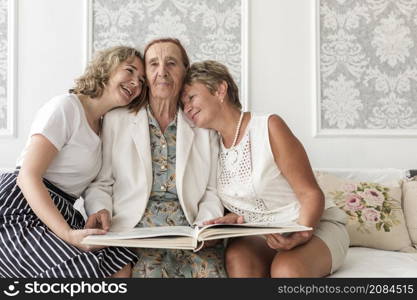 happy three generation women sitting sofa with holding album