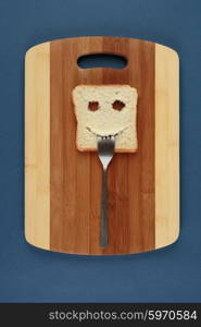 Happy toast with a fork in her mouth on a cutting board