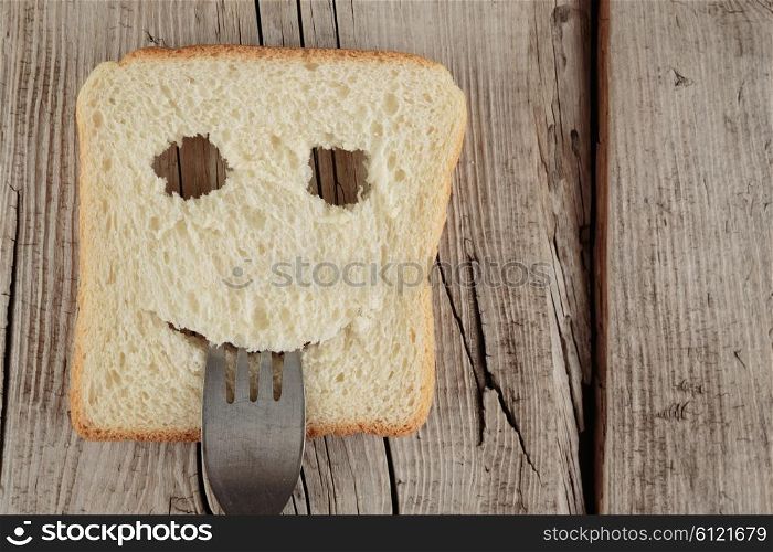 Happy toast with a fork in her mouth on a wooden cutting board