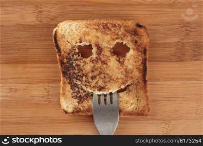 Happy toast with a fork in her mouth on a wooden cutting board