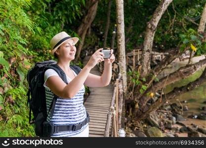 happy tourist on vacation photographs beautiful landscapes on the phone