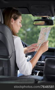 happy tourist reading a map inside a car on vacation