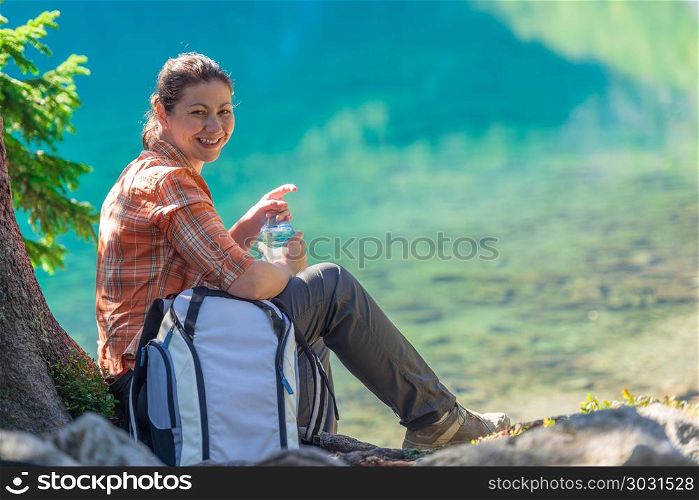 happy tourist with a bottle of water admires the beautiful mount. happy tourist with a bottle of water admires the beautiful mountain lake in the Tatras