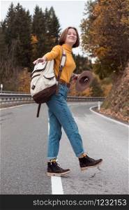 happy trip girl goes along the dividing strip road with a backpack