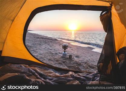 happy trip - view of the sea, burner, bowler, cup from the yellow tent on the beach at dawn. Ukrainian landscape at the Sea of Azov, Ukraine