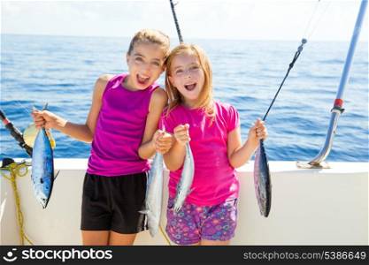 Happy tuna fisherwomen kid girls on boat with fishes trolling catch