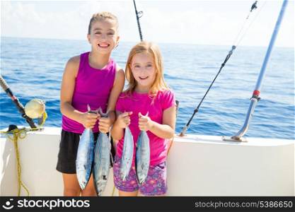 Happy tuna fisherwomen kid girls on boat with fishes trolling catch
