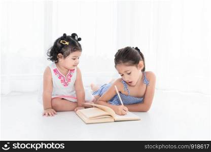 Happy two sister drawing in sketch book together at home or nursery. People lifestyle and kids play. Education and Children concept. Diverse ethnicity and ages. Back to school theme.