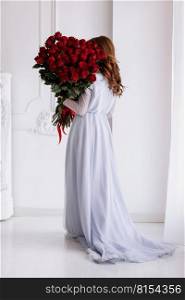 Happy Valentine’s Day. young woman in long dress holding a big luxury bouquet of red roses flowers. Celebration of engagement or wedding. Birthday gift. Happy Valentine’s Day. young woman in long dress holding a big luxury bouquet of red roses flowers. Celebration of engagement or wedding. Birthday gift.