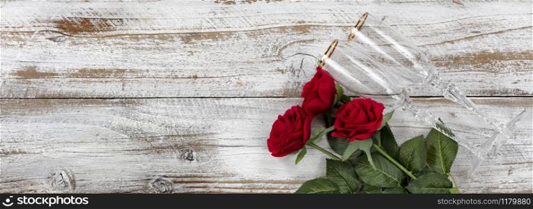 Happy Valentines Day celebration with red roses and drinking glasses on white rustic wooden background