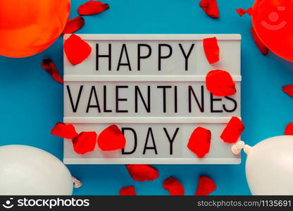 Happy Valentines Day lightbox message with red flower petals and balloons. Horizontal Image. Top view.