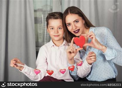 Happy Valentines Day or Mother day. Young boy spend time with her mum and celebrate with gingerbread heart cookies on a stick.. Happy Valentines or mother day