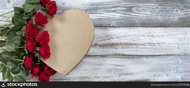 Happy Valentines Day with red roses on top of a heart shaped gift box with white rustic wooden background