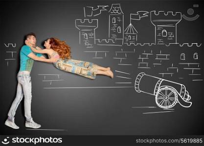 Happy valentines love story concept of a romantic couple against chalk drawings background. Male catching his girlfriend launched as a human cannonball.