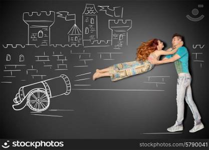 Happy valentines love story concept of a romantic couple against chalk drawings background. Male catching his girlfriend launched as a human cannonball.