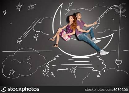 Happy valentines love story concept of a romantic couple fishing on a moon with a heart on a hook against chalk drawings background.